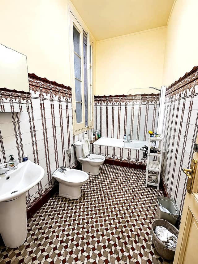 Baño con azulejos antiguos y bañera antes de la reforma